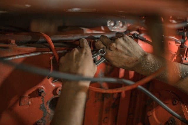 A close up shot of a man working on repairing a vehicle, with just his hands on shot